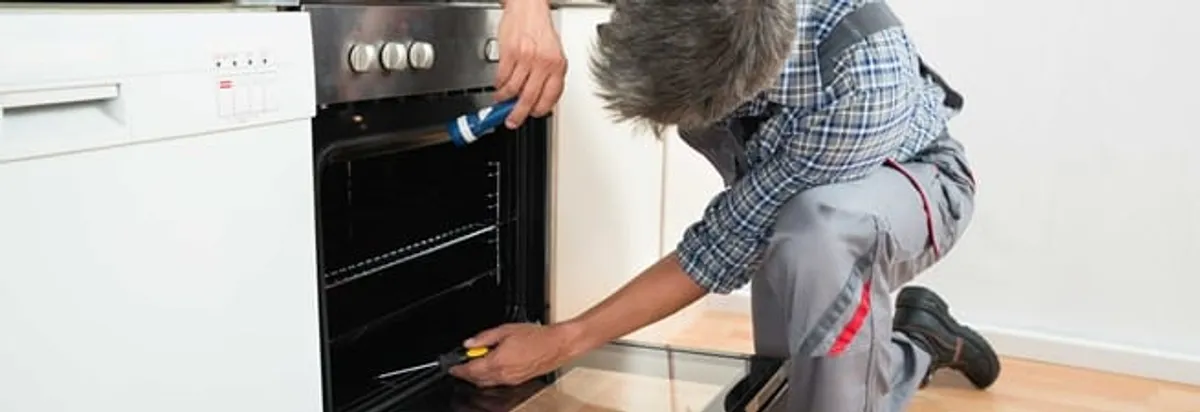 Oven repair technician inspecting and servicing an electric oven in Baltimore, MD