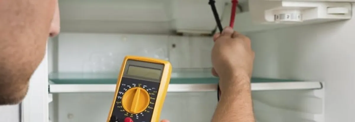 Refrigerator repair technician testing electrical components with a multimeter in Baltimore, MD